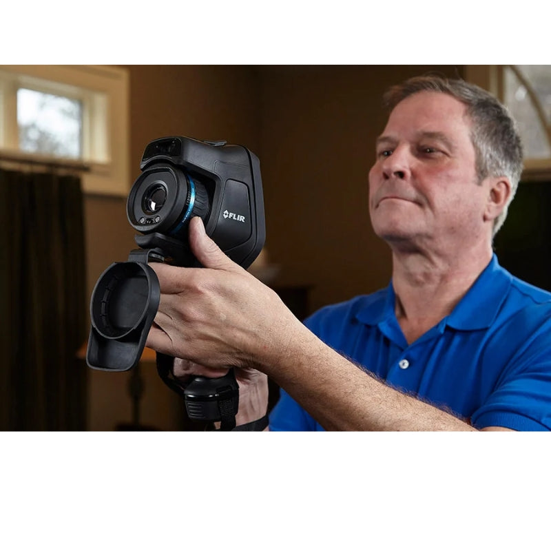 Man holding a FLIR FLIRE86 camera in an indoor setting